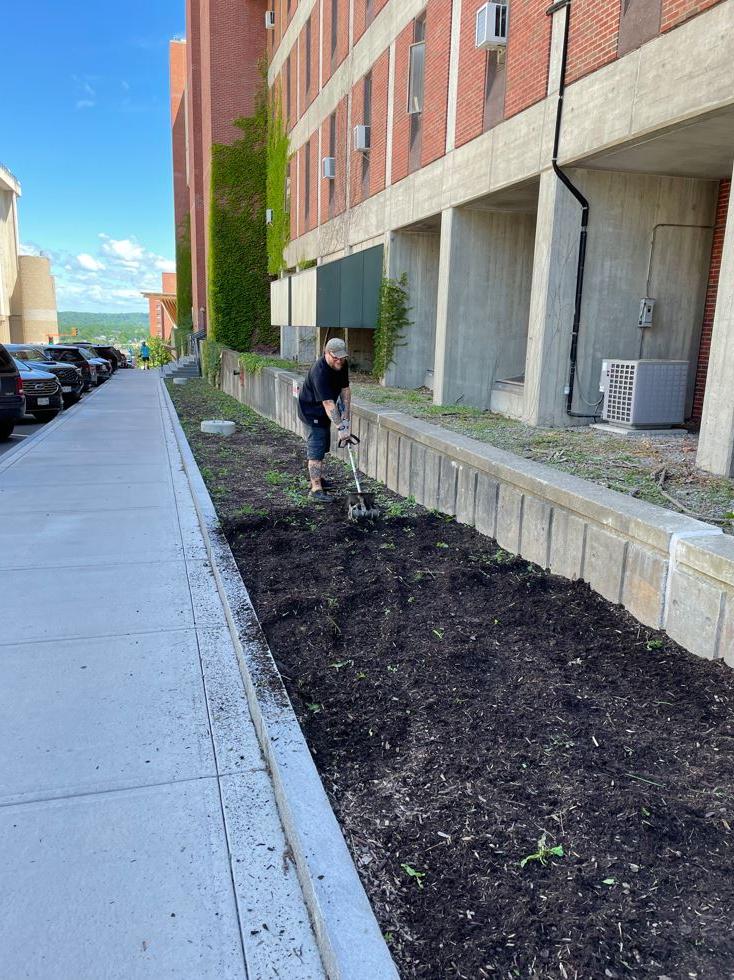 grounds crew member tilling a landscape bed with electric tiller